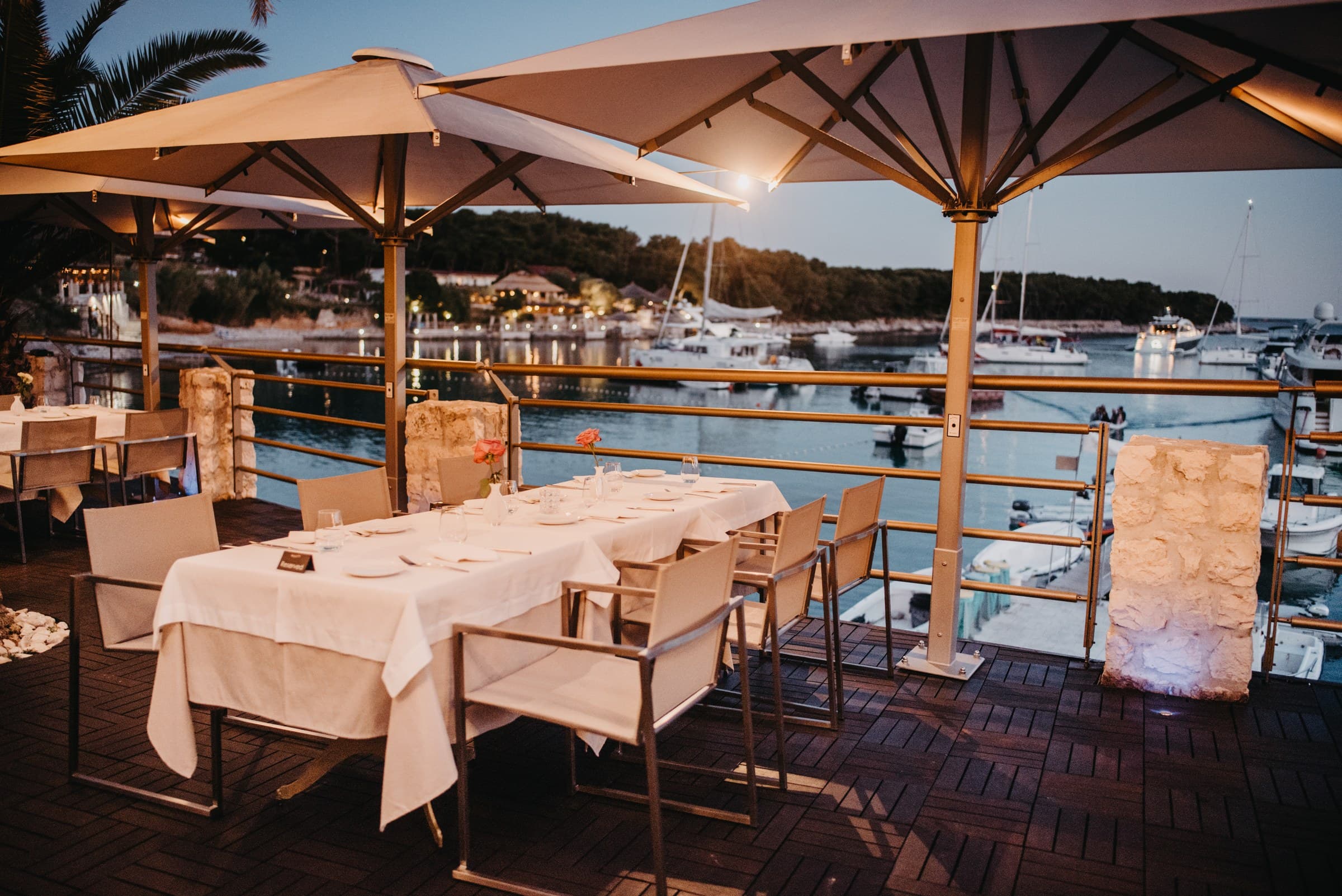 The Zori restaurant terrace at night on the Palmižana waterfront, lanterns above the Adriatic
